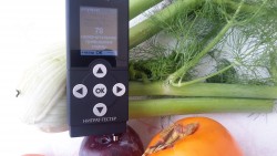 Нитрат-тестер на фоне овощей с результатом измерения