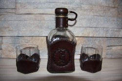 Стеклянная бутылка с кожаной оберткой и двумя стаканами