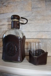 Стеклянная бутылка и стакан в кожаной обертке