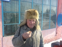 Мужчина в шубе и шапке держит еду на фоне здания