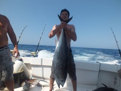 Молодой человек держит большую рыбу на лодке