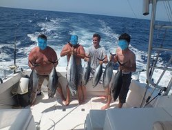 Четыре человека с рыбой на лодке в открытом море