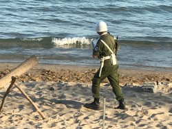 Солдат на пляже рядом с водой, ведет наблюдение