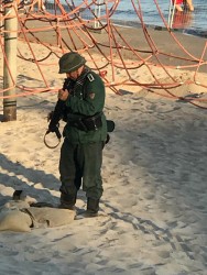 Военнослужащий с оружием на пляже, песок и сеть