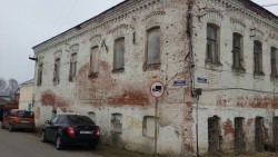 Старое здание с обветшалой кирпичной стеной и окнами