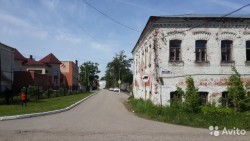 Улица с заброшенным зданием и зелеными насаждениями