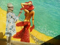 Женщина рисует на стене с изображением пляжа