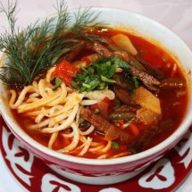 Суп с лапшой, мясом и зеленью в тарелке