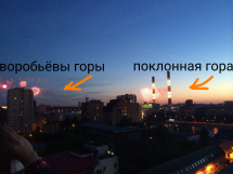 Вид на вечерний город с фейерверками и горами