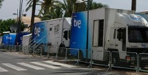 Грузовики телевизионной компании на улице под пальмами