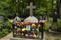 Могила, окруженная цветами и крестом, в лесу