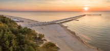 Закат над пляжем с пирсом и спокойным морем