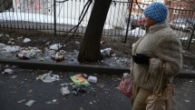 Женщина в шапке идет мимо мусора на улице