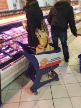 Собака сидит в тележке для покупок в магазине