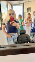 Женщина с длинными волосами в очках делает селфи в салоне