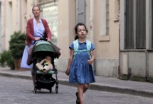 Девочка в синем платье идет по улице, женщина с коляской сзади