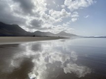 Пейзаж с пляжем, горами и отражением облаков в воде