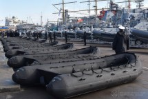 Ряд черных надувных лодок на причале с кораблями