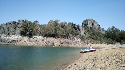 Пляж с каменистым берегом и лодкой на воде в Испании