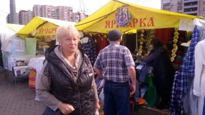 Женщина на ярмарке, вокруг палатки с товарами