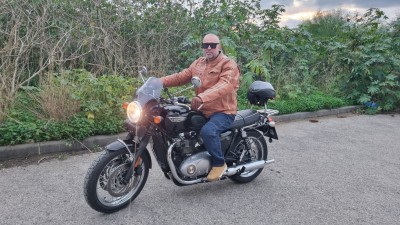 Мужчина в кожаном куртке на мотоцикле Triumph