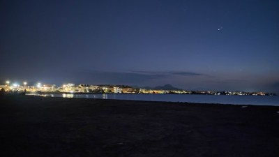 Ночной пляж с огнями на горизонте и спокойной водой в Испании
