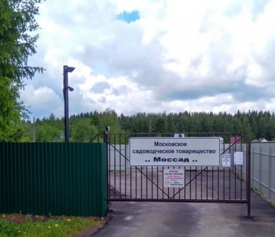 Ворота садоводческого товарищества с зелеными деревьями на фоне