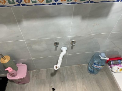 Смеситель и пластиковая труба на стене ванной комнаты