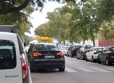 Чёрный автомобиль Tesla на улице среди припаркованных машин в Испании