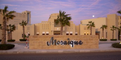 Здание с вывеской "Mosaïque" и пальмами на фоне заката в Испании
