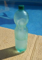 Пластиковая бутылка с водой рядом с бассейном