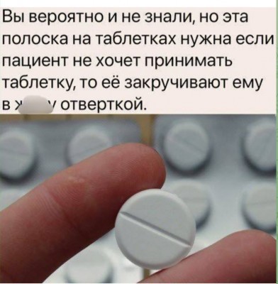 Белая таблетка с бороздкой на поверхности в руке