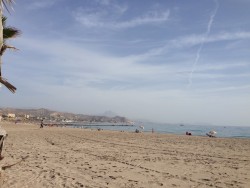 Песчаный пляж с отдыхающими и морем на горизонте