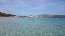 Люди купаются в прозрачной воде на пляже