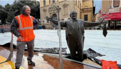 Рабочий в оранжевом жилете рядом с бронзовой статуей (в Испании)