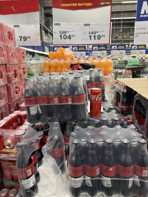 Упаковки с напитками в супермаркете, ценники на товары