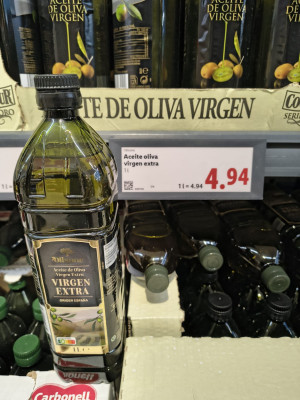 На фото бутылка оливкового масла "virgen extra" на полке магазина.