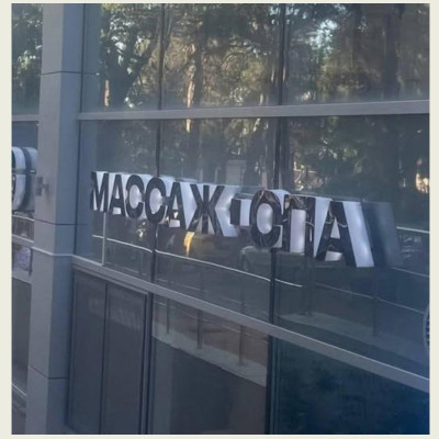 На фото виден стеклянный фасад с вывеской "МАССАЖ", в Испании