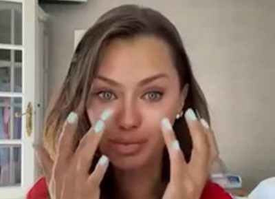 Женщина с длинными волосами показывает на лицо, в комнате.