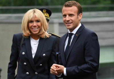На фото Эммануэль и Брижит Macron, улыбающиеся на встрече.