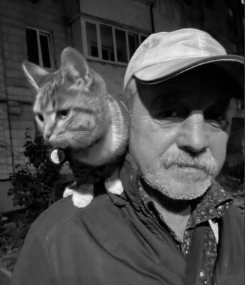 Мужчина с белой бородой и кошка на его плече.