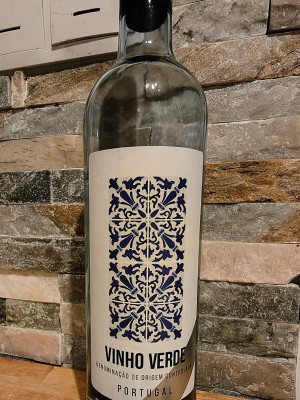 Бутылка вина Vinho Verde на фоне каменной стены.