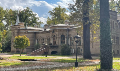 Старинное здание в парке с зелеными деревьями, в Испании