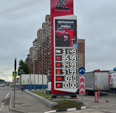 Заправочная станция с ценами на топливо и рекламой мойки.