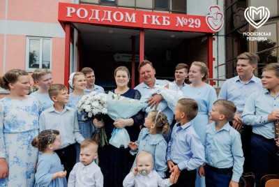 Семья с цветами у роддома, радующаяся новому прибывшему, в Испании