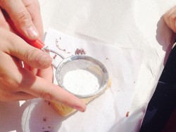 Рука с ситом, посыпающим сахар на печенье