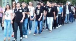 Группа молодых людей идет по улице, держась за руки