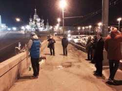 Люди на мосту, цветы и собор на фоне. Ночная сцена