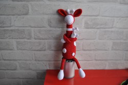 Вязаная игрушка жирафа красного цвета с белыми пятнами