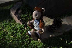 Вязаная игрушка коровы на камне среди травы